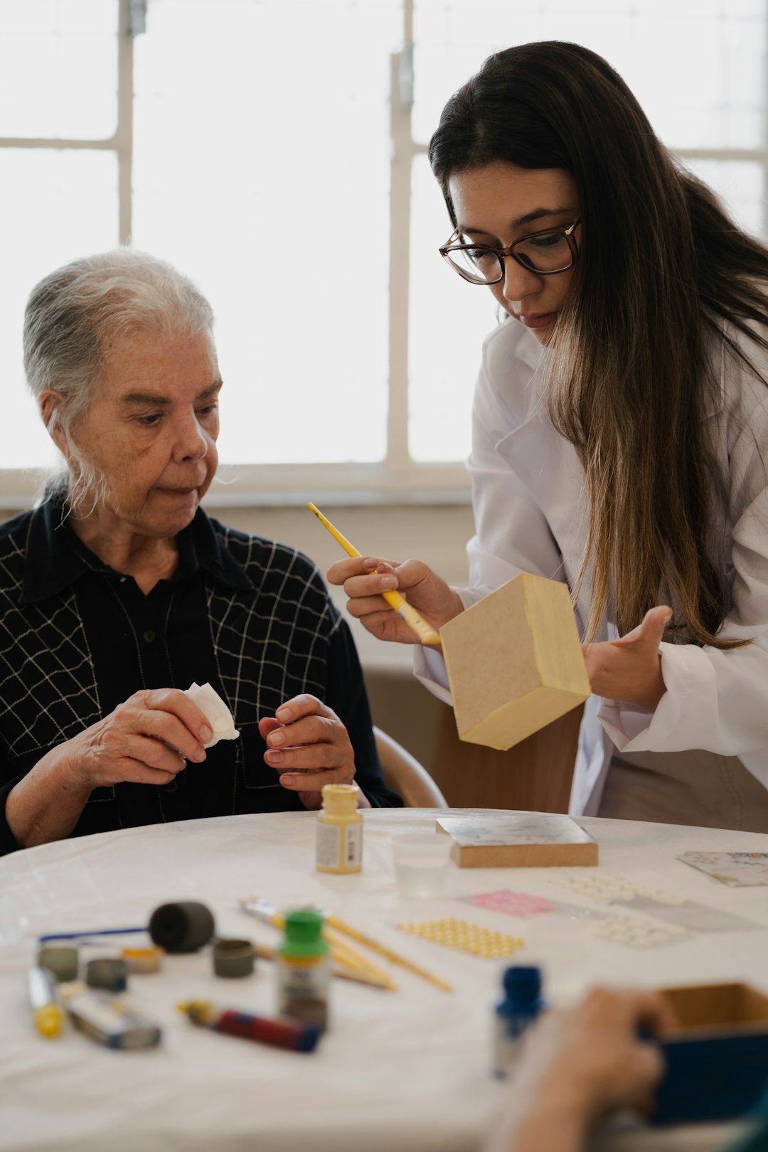Occupational therapist guiding an older woman through a hands-on activity in a care home